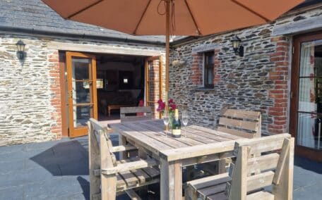 The level patio opens up from the sitting room and is equipped with outdoor furniture and a BBQ