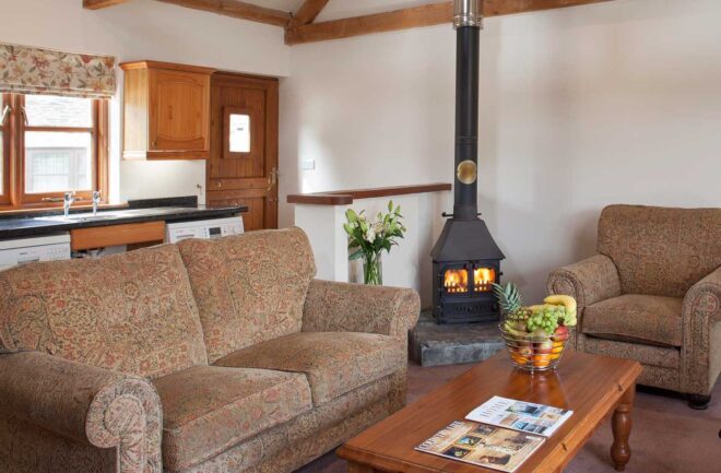 The open plan sitting room in Buzzard Watch with sofas, electric riser recliner chair and woodburner