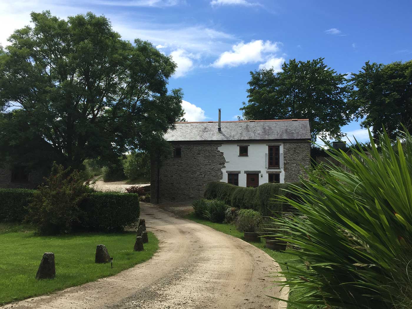 View down the concrete drive to Valley View beside hedges and flowers