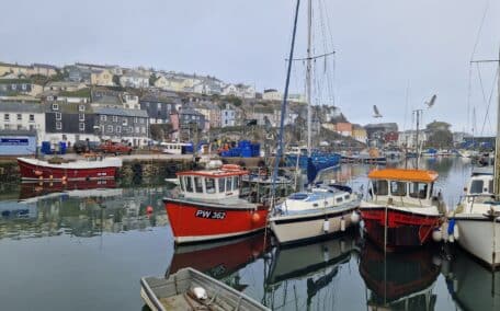 Reflections in the mirror like water of the fishing boats in Mevagissey harbour